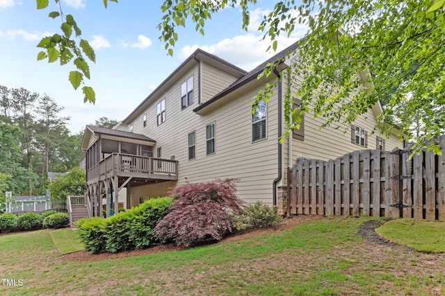 view of property exterior featuring a sunroom, stairway, and a wooden deck