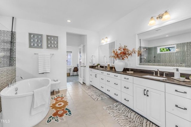 bathroom with double vanity, walk in shower, a freestanding tub, tile patterned floors, and recessed lighting