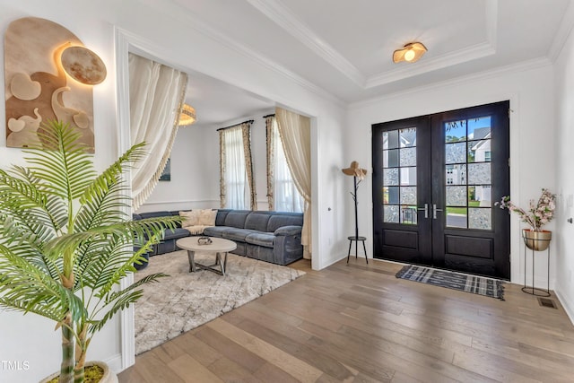 entryway with wood-type flooring, french doors, a raised ceiling, baseboards, and ornamental molding