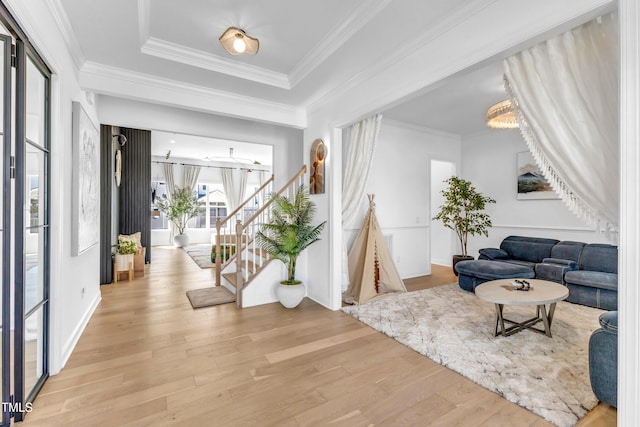 entryway featuring wood finished floors, stairs, ornamental molding, and a tray ceiling