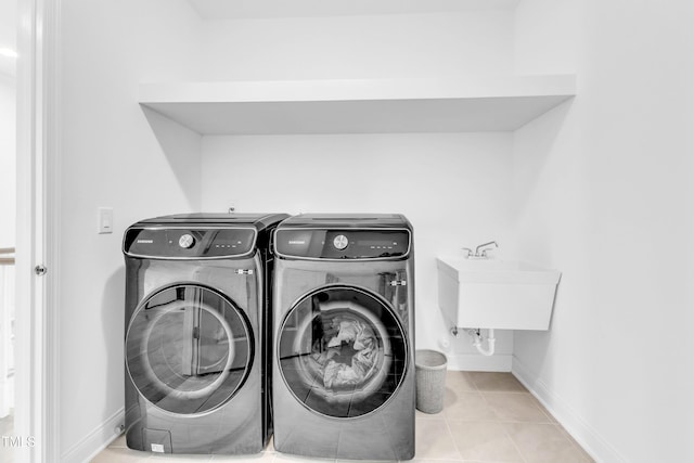 washroom with washer and dryer, baseboards, and tile patterned flooring