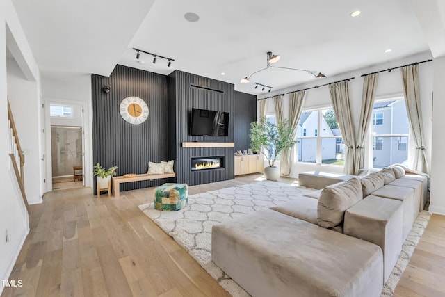 living area with baseboards, light wood-style floors, rail lighting, a fireplace, and recessed lighting