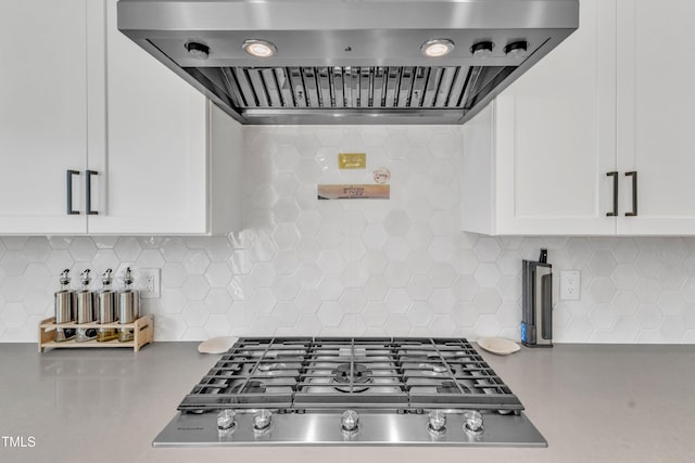 kitchen with wall chimney exhaust hood, stainless steel gas stovetop, decorative backsplash, and white cabinets