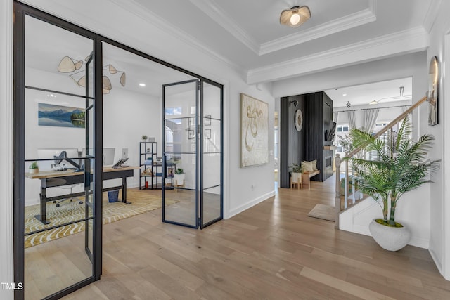 entryway with light wood finished floors, baseboards, crown molding, and stairway