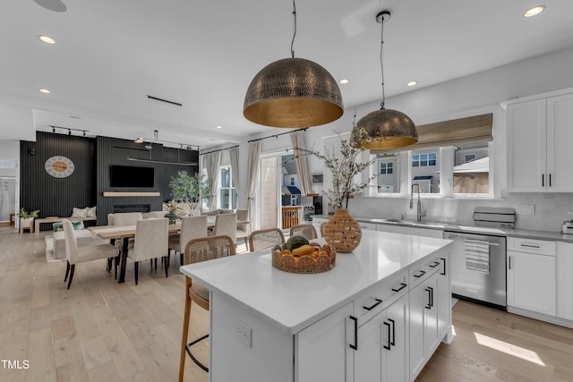kitchen featuring stainless steel dishwasher, a sink, white cabinets, light countertops, and recessed lighting