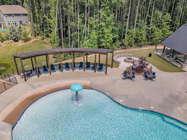 view of swimming pool with a fire pit, a gazebo, a patio area, and a wooded view