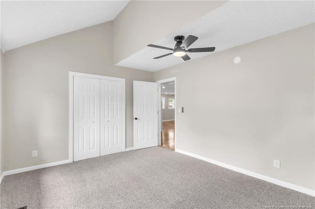 unfurnished bedroom featuring a closet, carpet flooring, baseboards, lofted ceiling, and a ceiling fan