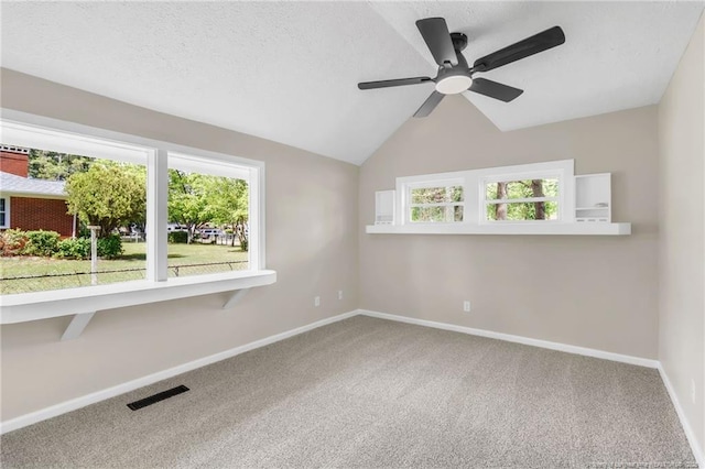 carpeted spare room with a ceiling fan, plenty of natural light, baseboards, and lofted ceiling