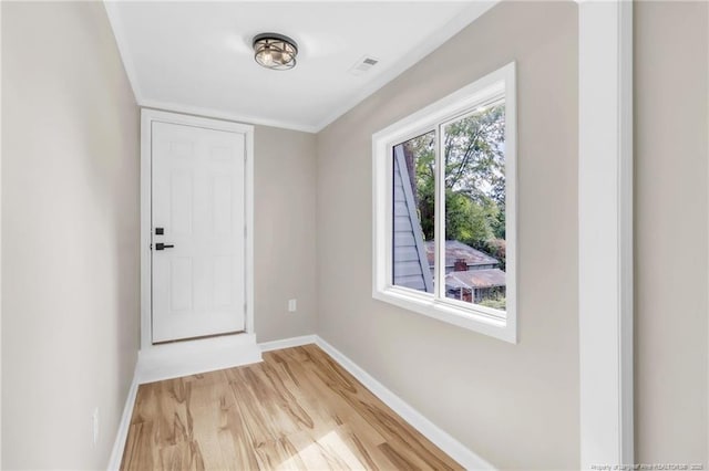 doorway featuring baseboards, light wood-style flooring, and crown molding