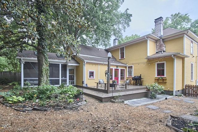 back of house with a sunroom, a chimney, a deck, and fence