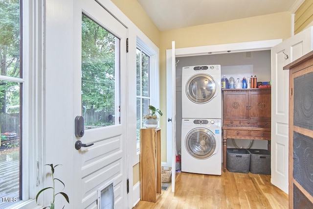 laundry room with stacked washing machine and dryer and light wood finished floors