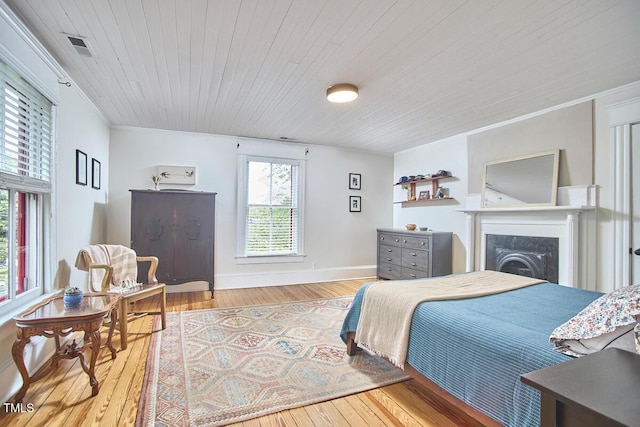 bedroom featuring wood finished floors, a fireplace, wooden ceiling, crown molding, and baseboards