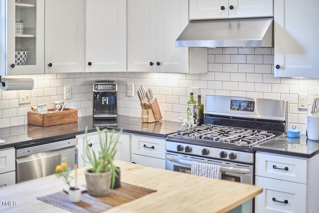 kitchen with stainless steel appliances, under cabinet range hood, white cabinets, glass insert cabinets, and decorative backsplash