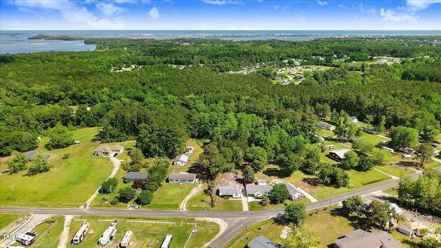 aerial view of property and surrounding area with a heavily wooded area and a nearby body of water