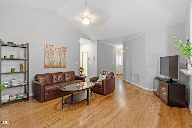 living room with light wood finished floors, lofted ceiling, and baseboards