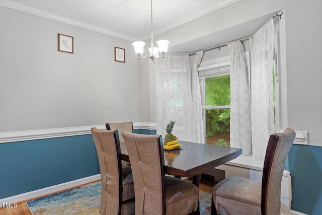 dining area with a chandelier, crown molding, baseboards, and wood finished floors