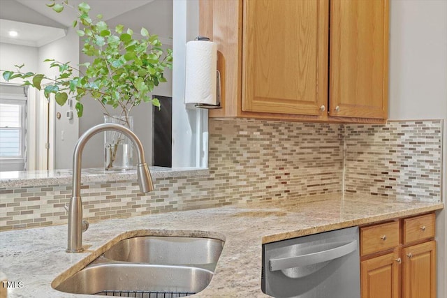 kitchen with dishwasher, decorative backsplash, a sink, light stone countertops, and vaulted ceiling
