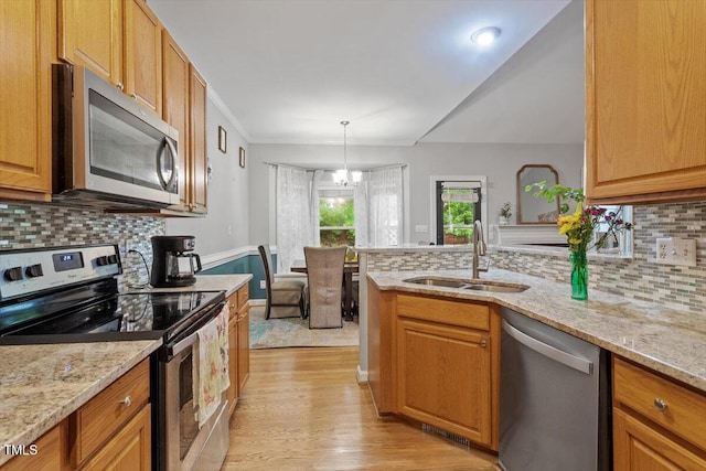 kitchen with appliances with stainless steel finishes, a sink, light wood finished floors, decorative backsplash, and lofted ceiling