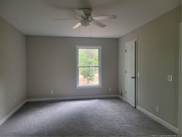 carpeted spare room with a ceiling fan and baseboards