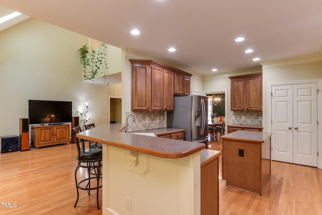 119 Marykirk Pl, Garner, NC 27529 - kitchen featuring stainless steel refrigerator with ice dispenser, a breakfast bar area, backsplash, a peninsula, and light wood-style flooring