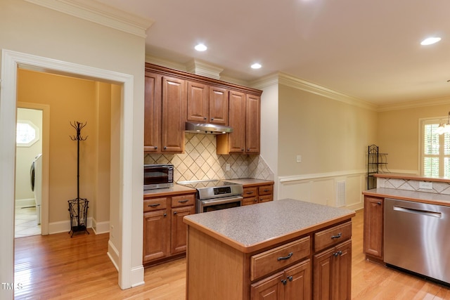 119 Marykirk Pl, Garner, NC 27529 - kitchen featuring appliances with stainless steel finishes, under cabinet range hood, light wood-style flooring, light countertops, and crown molding