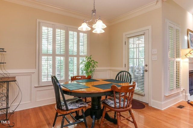 119 Marykirk Pl, Garner, NC 27529 - dining room featuring light wood-style flooring, a chandelier, wainscoting, ornamental molding, and a decorative wall