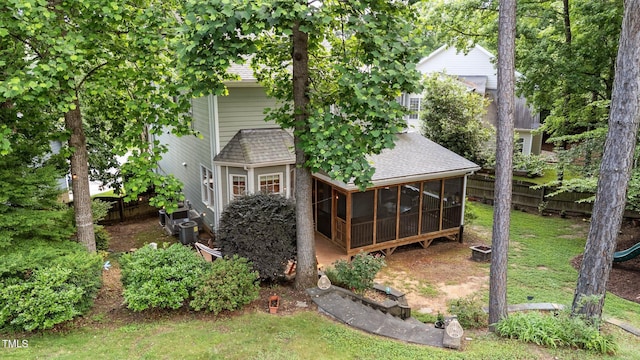 back of house featuring a sunroom, roof with shingles, and central AC