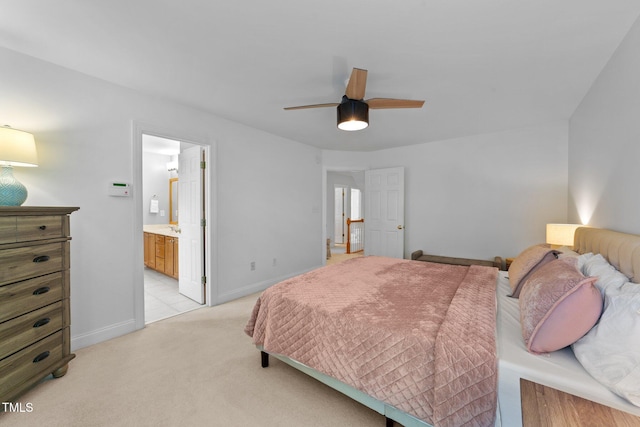 bedroom with light colored carpet, baseboards, ensuite bath, and a ceiling fan