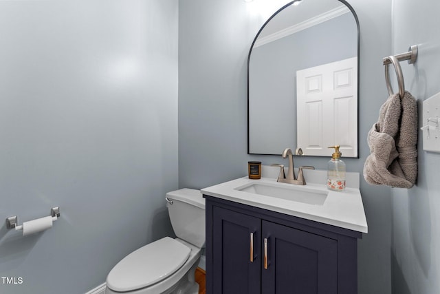 bathroom featuring toilet, crown molding, vanity, and baseboards