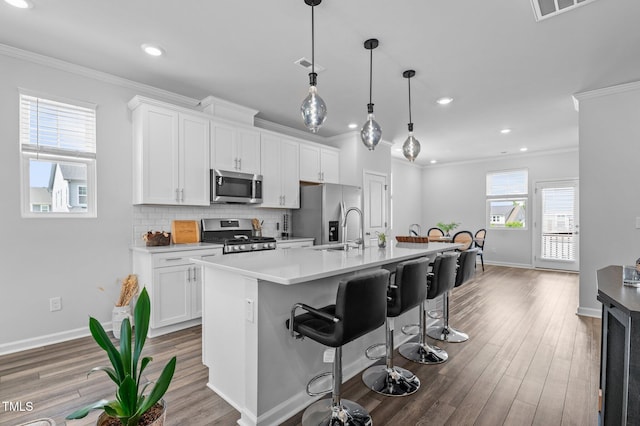 6352 Perry Creek Rd, Raleigh, NC 27616 - kitchen with appliances with stainless steel finishes, ornamental molding, baseboards, a center island with sink, and white cabinetry