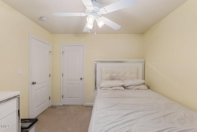 bedroom featuring light carpet, a ceiling fan, and baseboards