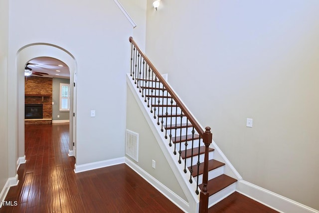 337 Shadowdale Ln, Rolesville, NC 27571 - stairs with hardwood / wood-style flooring, ceiling fan, baseboards, a stone fireplace, and arched walkways