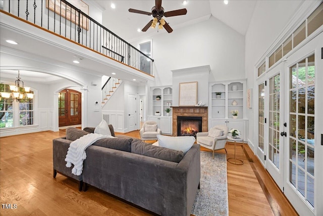 2507 Mayview Rd, Raleigh, NC 27607 - living area with high vaulted ceiling, a warm lit fireplace, a ceiling fan, wood finished floors, and a chandelier