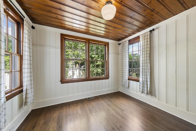 empty room featuring wooden ceiling, a decorative wall, dark wood-style flooring, and baseboards