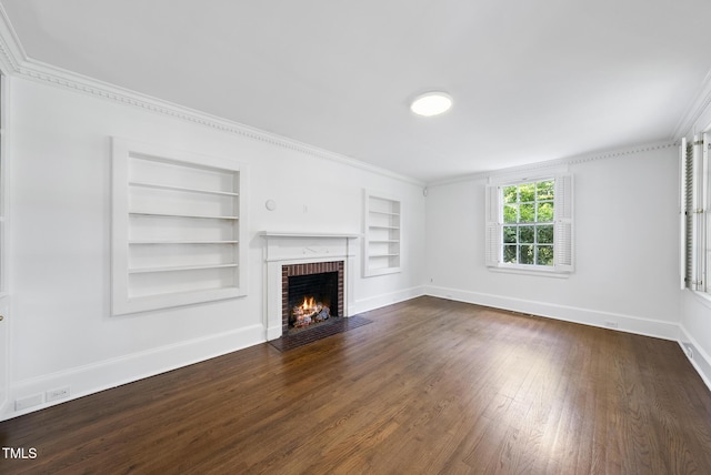 unfurnished living room with built in features, baseboards, dark wood finished floors, ornamental molding, and a brick fireplace