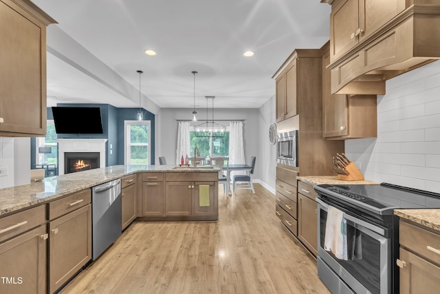 1109 Agio Ct, Zebulon, NC 27597 - kitchen with appliances with stainless steel finishes, a sink, under cabinet range hood, light stone countertops, and light wood-type flooring