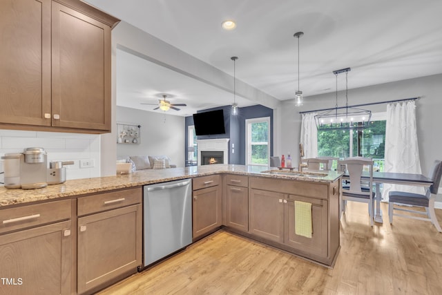 1109 Agio Ct, Zebulon, NC 27597 - kitchen featuring stainless steel dishwasher, a sink, a warm lit fireplace, light wood-style floors, and recessed lighting