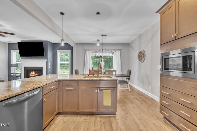 1109 Agio Ct, Zebulon, NC 27597 - kitchen with stainless steel appliances, a sink, light wood-style flooring, light stone counters, and baseboards