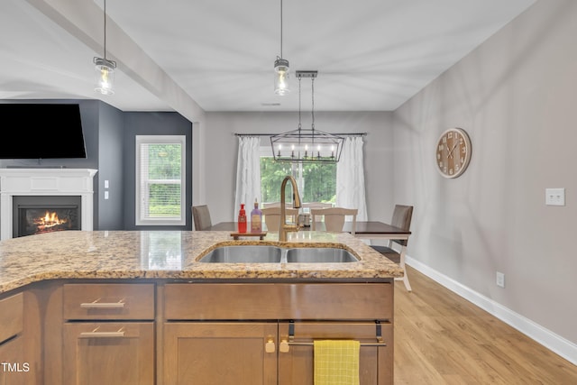 1109 Agio Ct, Zebulon, NC 27597 - kitchen featuring a sink, baseboards, light stone counters, light wood-style flooring, and open floor plan