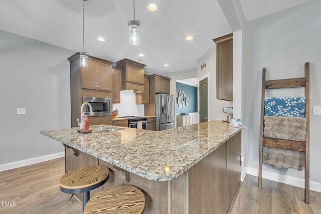 1109 Agio Ct, Zebulon, NC 27597 - kitchen with stainless steel appliances, baseboards, a sink, light stone counters, and recessed lighting