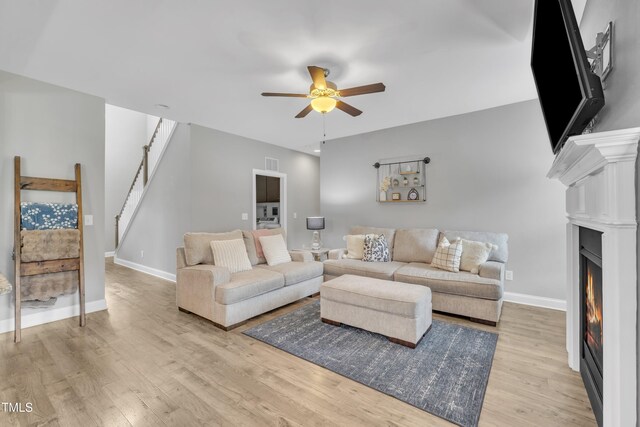 1109 Agio Ct, Zebulon, NC 27597 - living area with ceiling fan, light wood-style floors, a warm lit fireplace, and baseboards