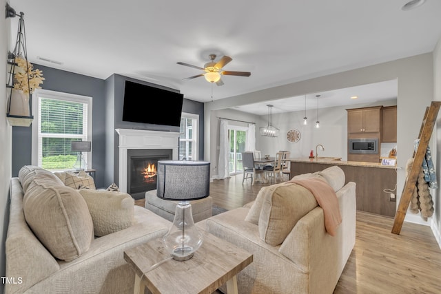 1109 Agio Ct, Zebulon, NC 27597 - living area with a glass covered fireplace, a ceiling fan, light wood-style floors, recessed lighting, and baseboards