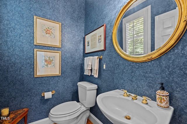 bathroom featuring a sink, toilet, and baseboards