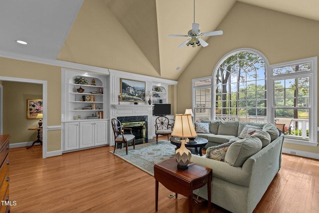 living room with ceiling fan, a premium fireplace, high vaulted ceiling, light wood-style floors, and baseboards