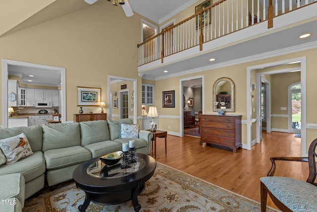 living room with high vaulted ceiling, wood finished floors, crown molding, baseboards, and ceiling fan