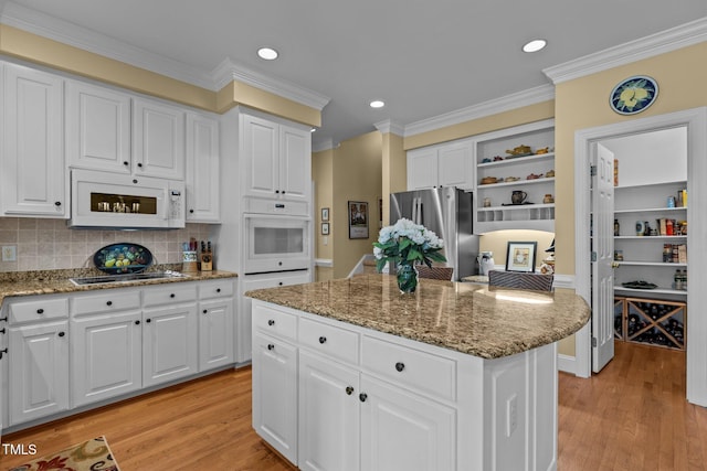 kitchen with white appliances, open shelves, a center island, light wood-type flooring, and crown molding