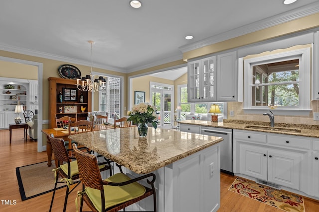 kitchen with stainless steel dishwasher, a sink, a kitchen bar, a center island, and light wood-style flooring