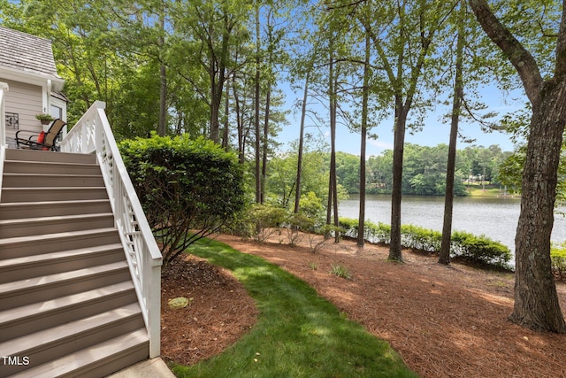 view of yard featuring a water view, stairway, and view of wooded area