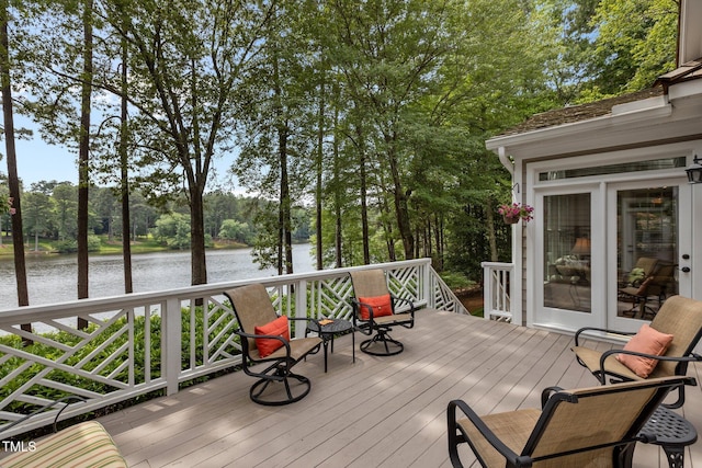 deck with a water view and view of wooded area