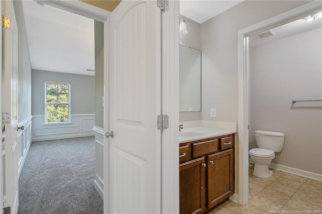 bathroom featuring toilet, vanity, and a wainscoted wall
